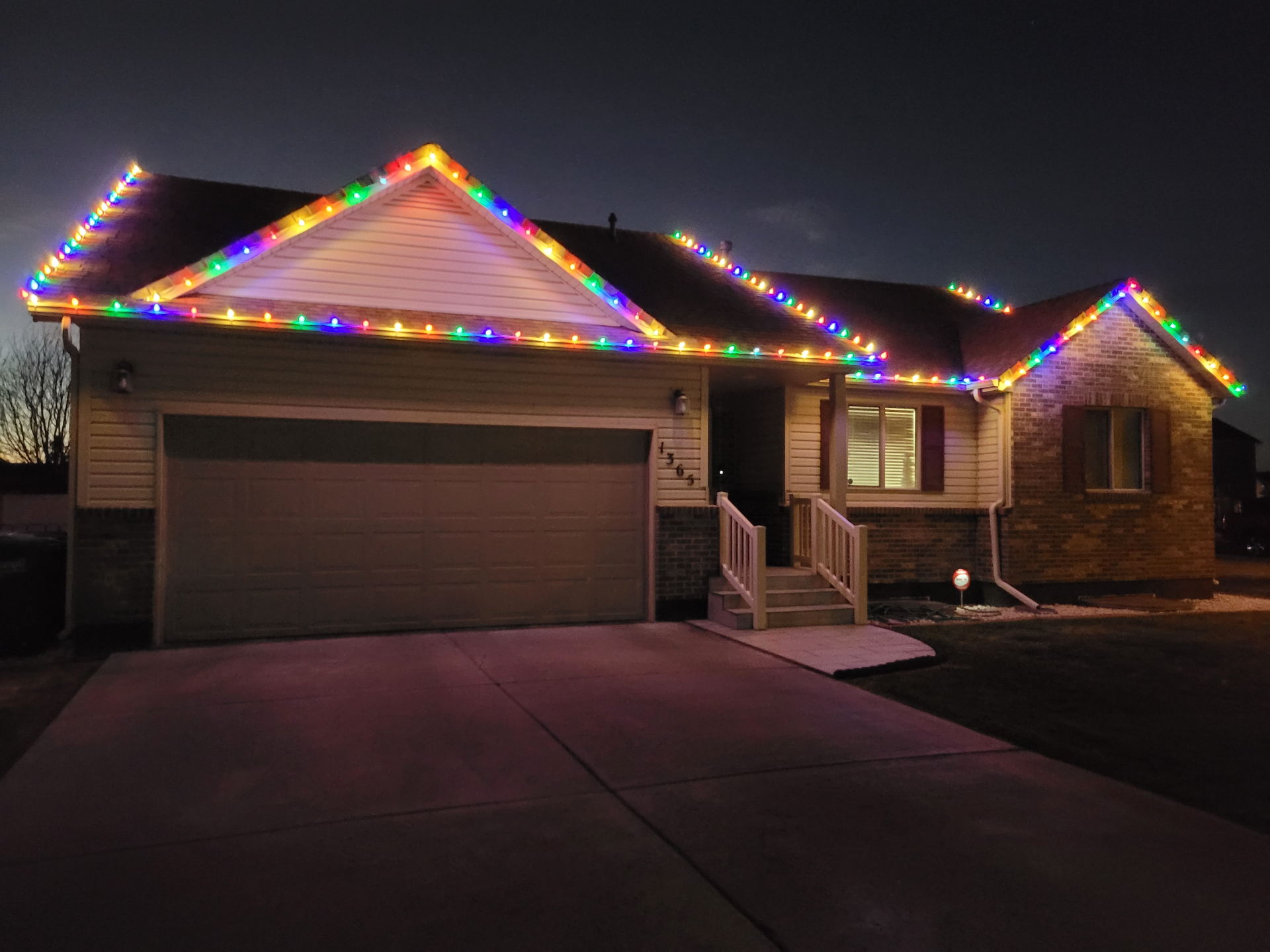 Home in Idaho Falls with multi-color C9 Christmas lights along the roofline at dusk