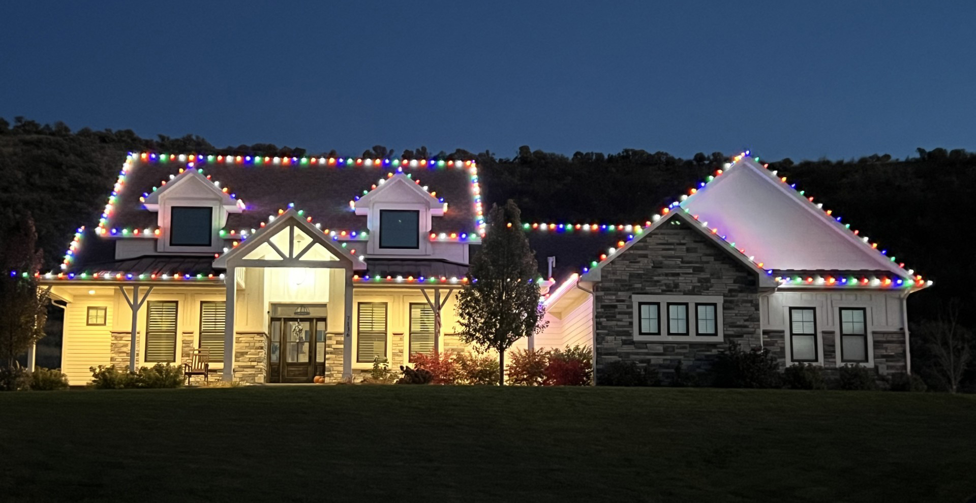 Home outlined with multi-color C9 Christmas lights at dusk in Idaho Falls