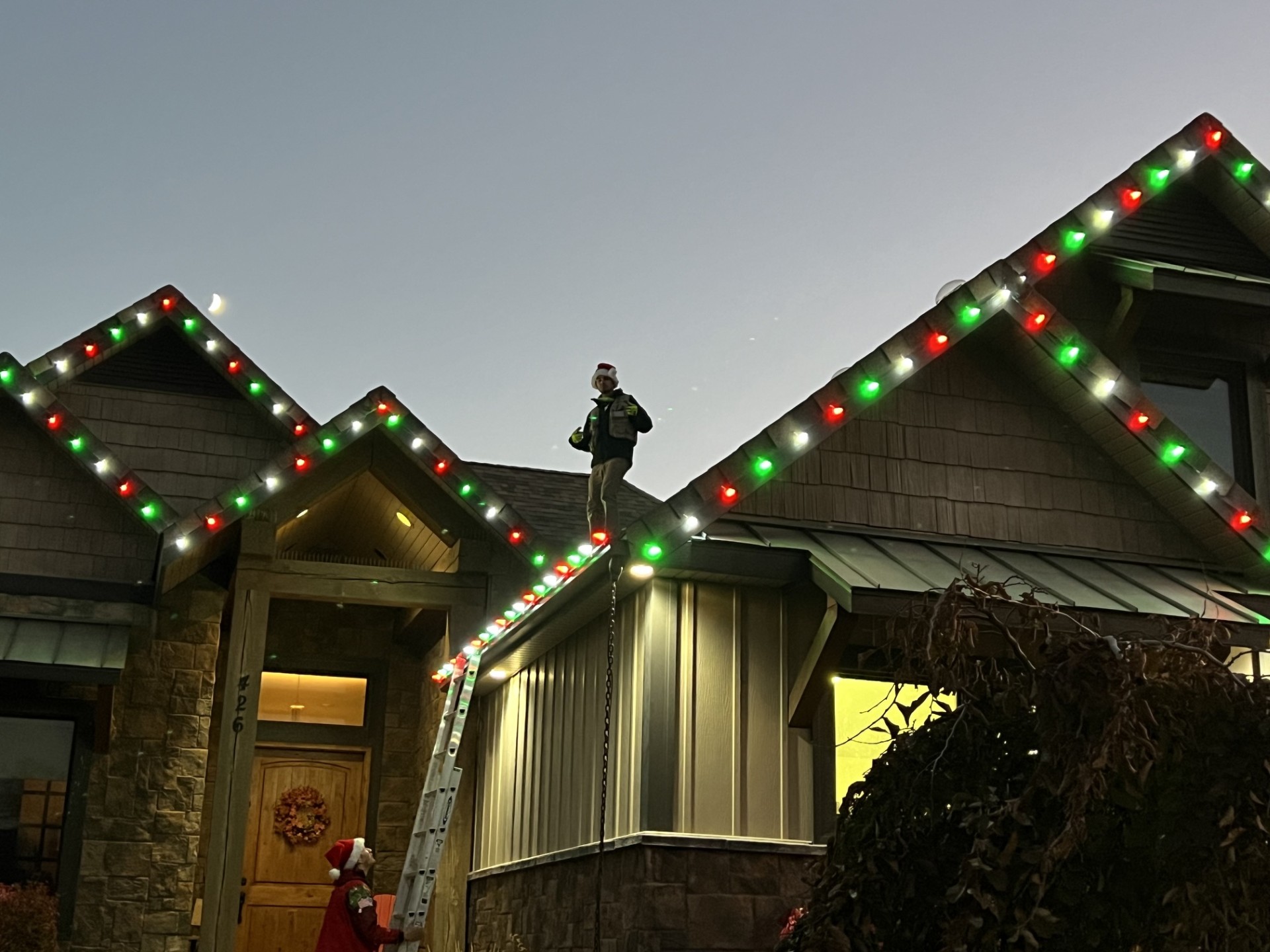 Installing a red, green and white C9 roofline at dusk.
