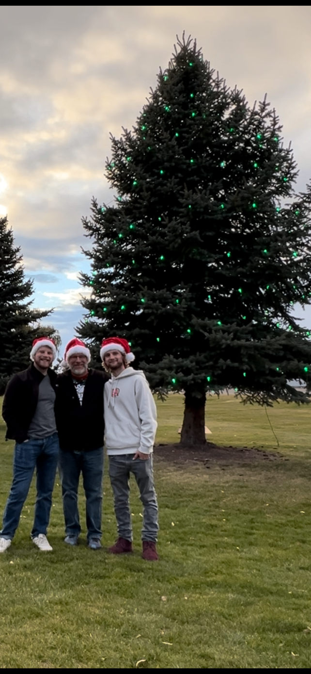 Santa's Magical Lights crew in front of a tree lit with green lights