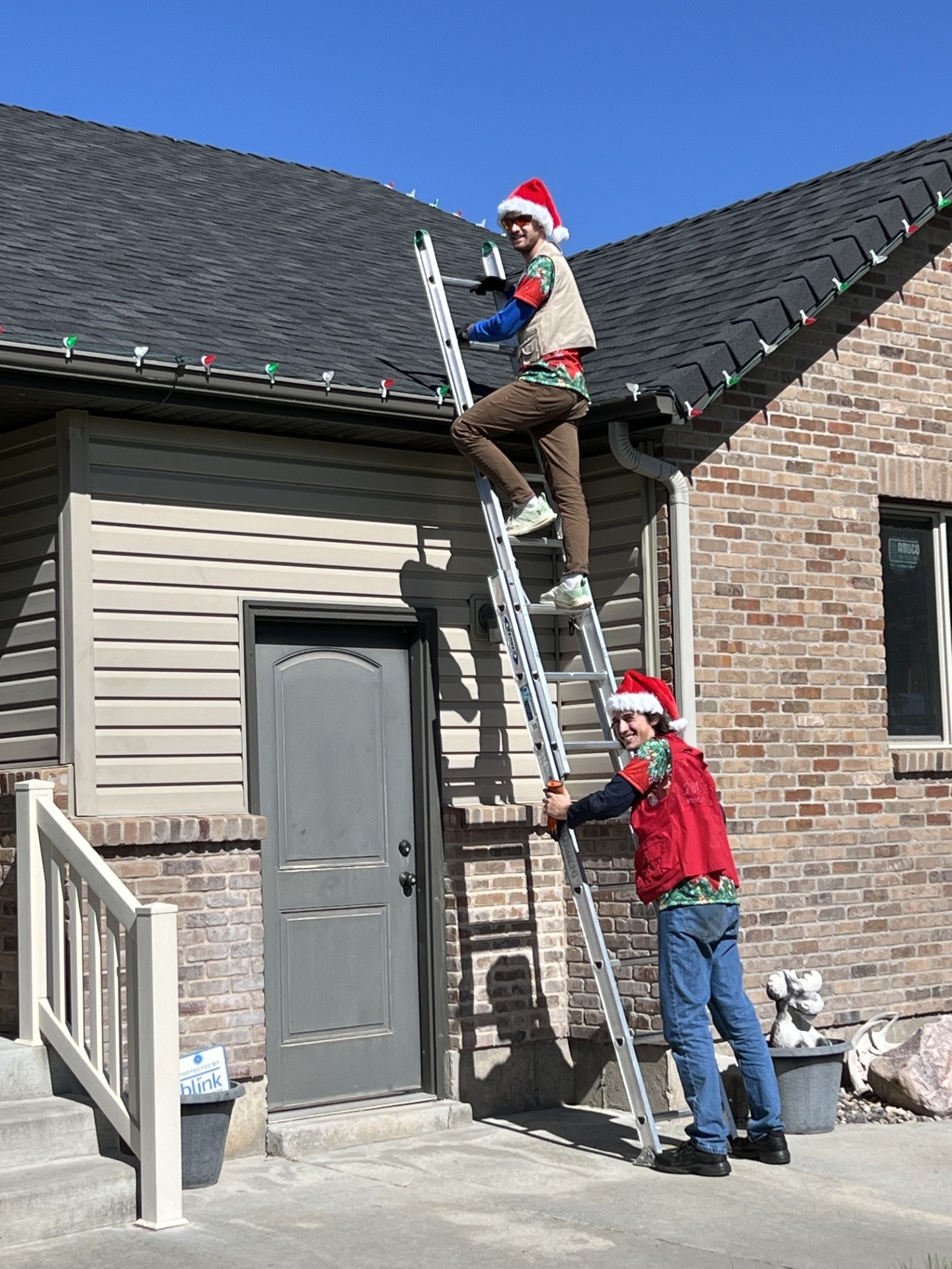 Installers working on Christmas light installation with ladder