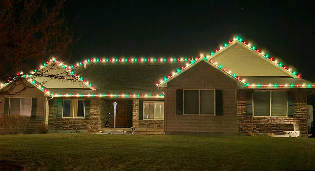 Stone-front home in Idaho Falls with red, green, and warm white C9 Christmas lights on the roofline