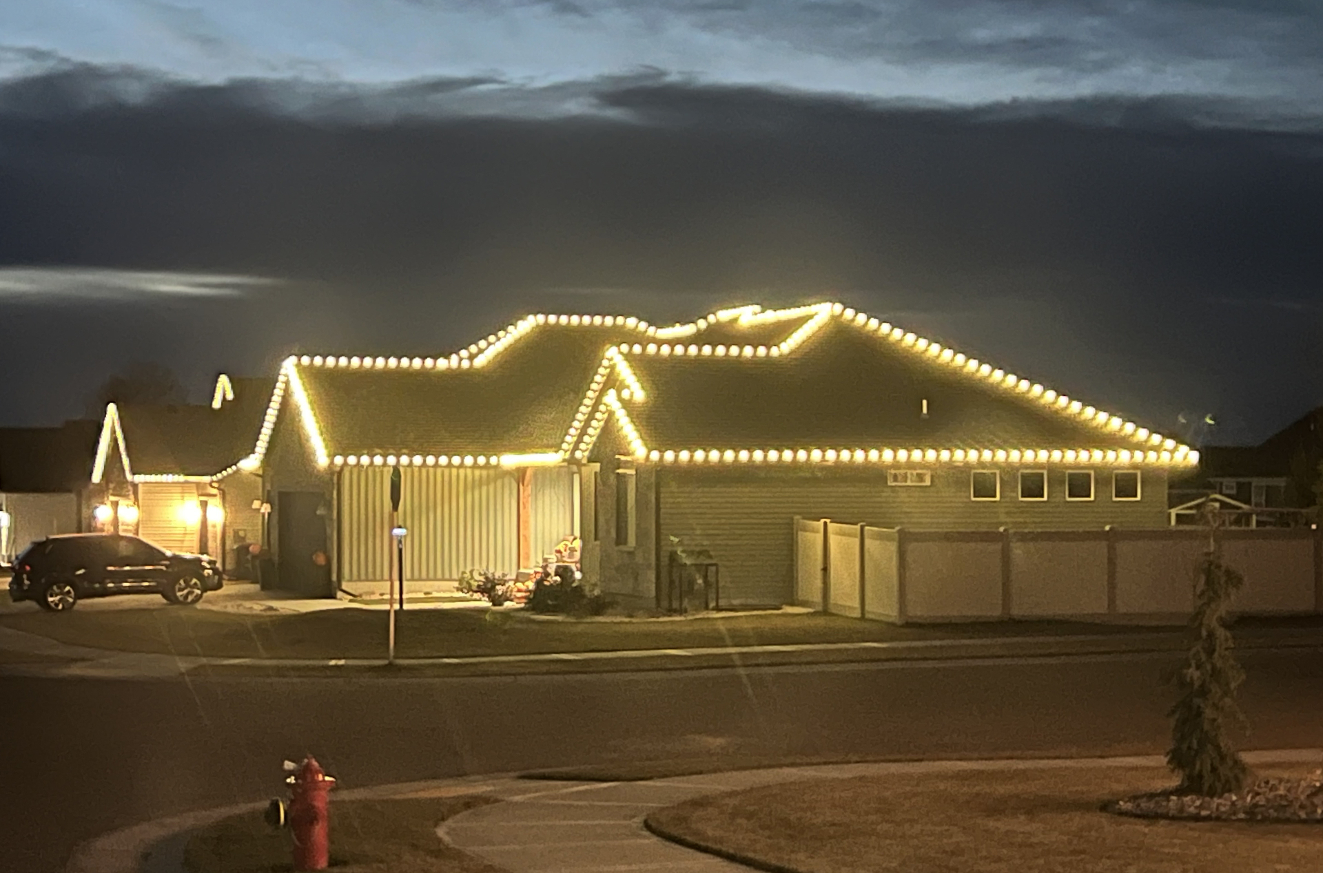 Single-story Ammon home with warm white C9 Christmas lights along the roof ridges and gables