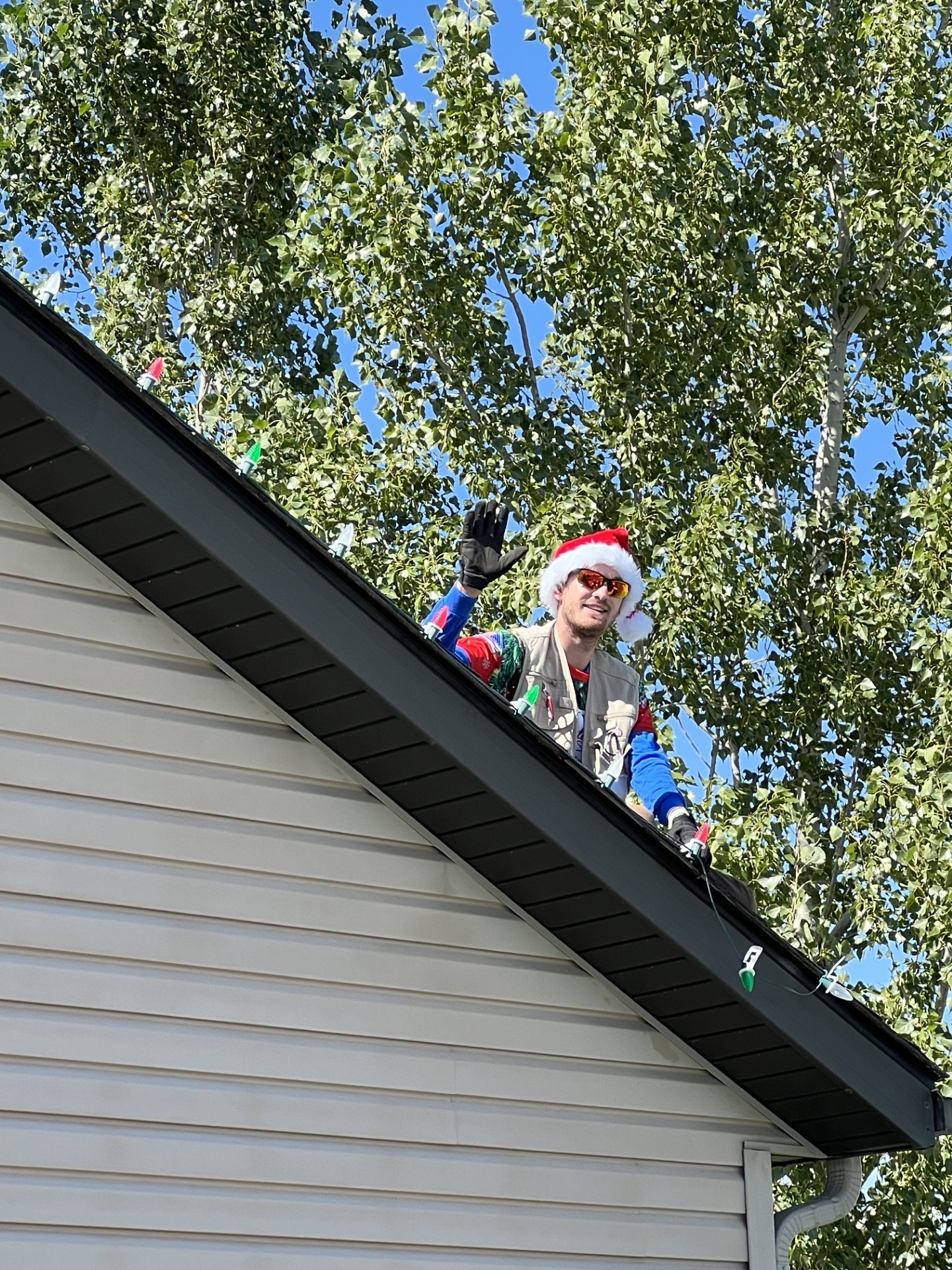Installer in Santa hat waving from rooftop